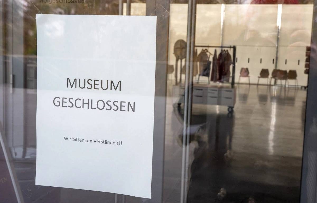 Sign reading 'MUSEUM CLOSED' in German posted to a glass door.