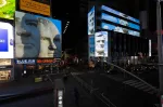 An empty street intersection filled with large billboards that show stone sculptures of serious-looking men.