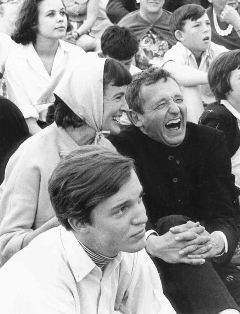 View of American artists Jamie Wyeth (fore) with his parents, Betsy Wyeth (1921 - 2020) and painter Andrew Wyeth (1917 - 2009), the latter two sharing a laugh, as they attend an unspecified wedding, Chadds Ford, Pennsylvania, 1959. (Photo by Jack Rosen/Getty Images)