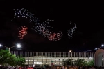 A double-helix swirl of red, blue, and white light is seen above a large building.