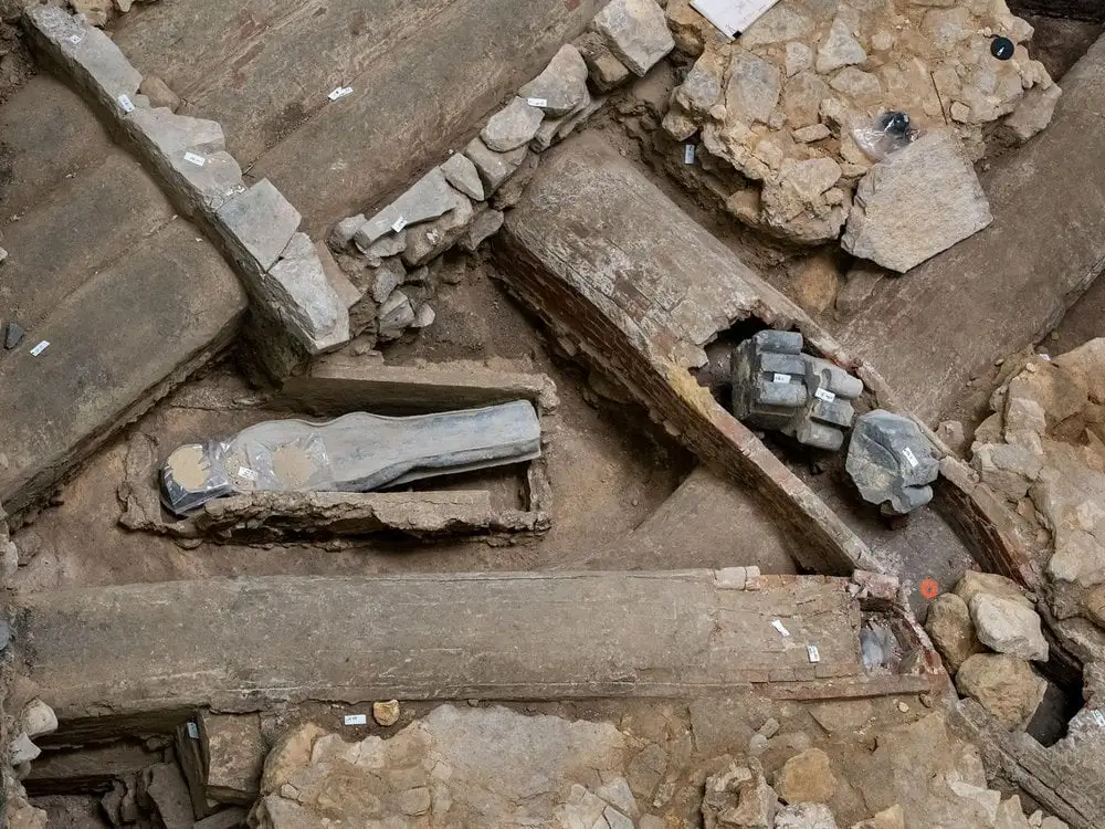 Two lead coffins laying amid stone rubble.
