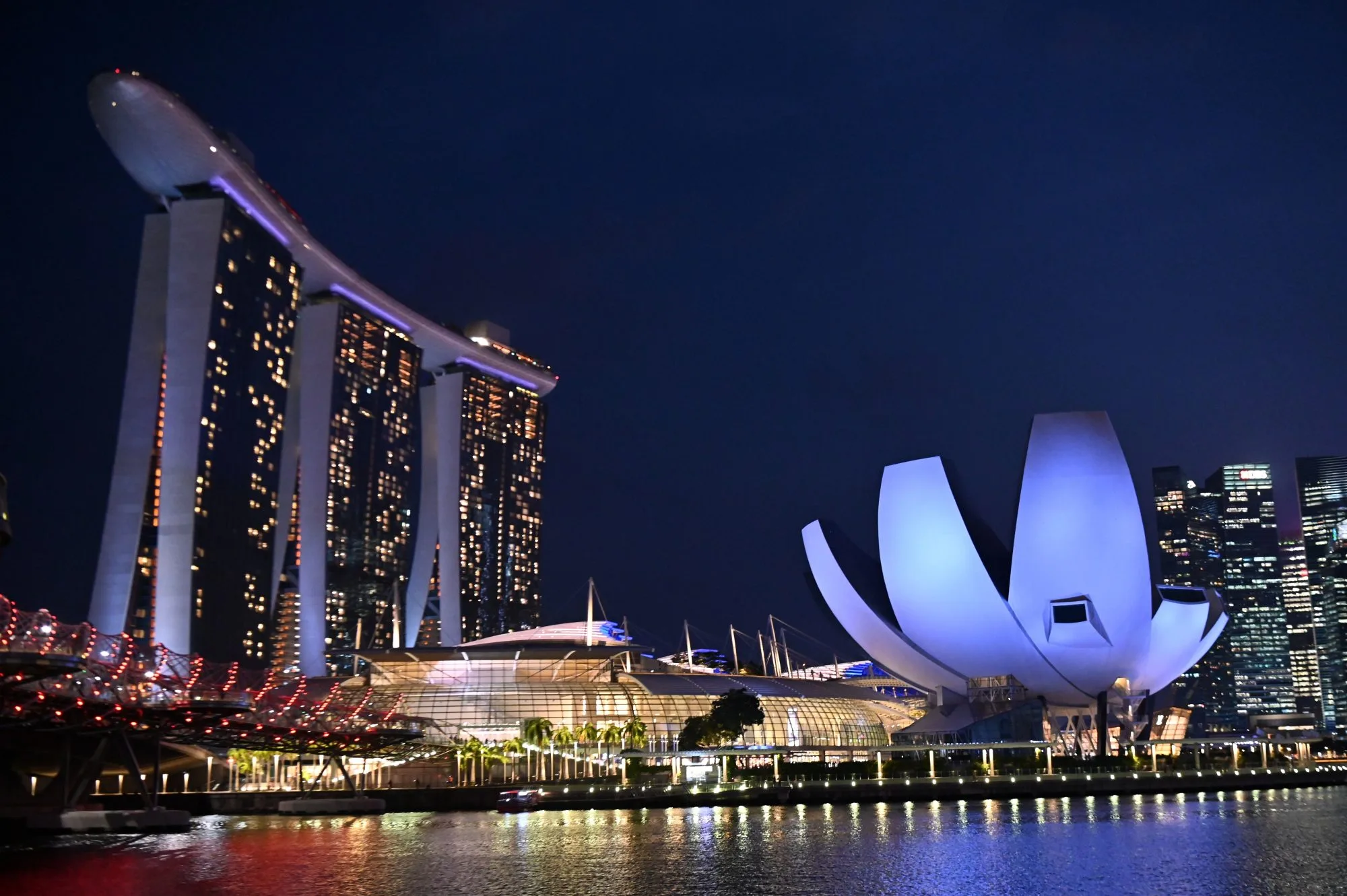 The Marina Bay Sands hotel and resorts (L) and the ArtScience Museum (R) are illuminated under the evening sky in Singapore on March 8, 2019.