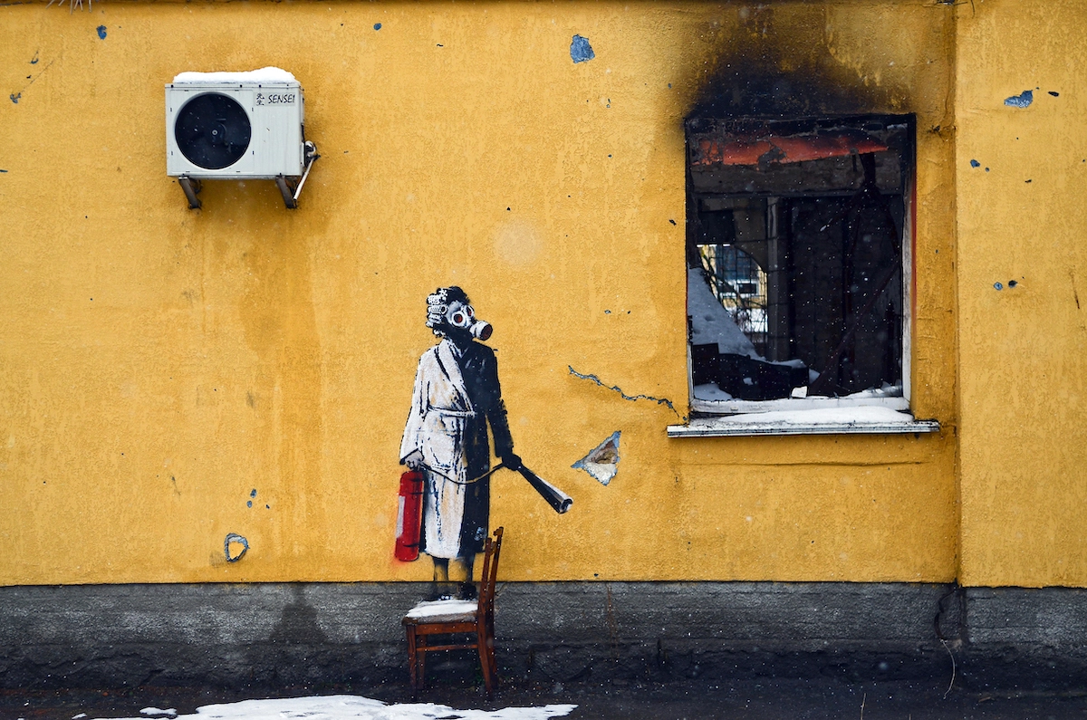 Mural displaying a woman in a gas mask on the wall of a house.