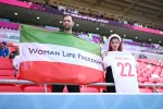 DOHA, QATAR - NOVEMBER 25: Fans hold up a shirt with the name of Mahsa Amini and a flag advocating for women's rights prior to the FIFA World Cup Qatar 2022 Group B match between Wales and IR Iran at Ahmad Bin Ali Stadium on November 25, 2022, in Doha, Qatar. People have continued demonstrating in Iran over the death of Mahsa Amini in September. Mahsa Amini fell into a coma and died after being arrested in Tehran by morality police, for allegedly violating the country's hijab rules. (Photo by Matthias Hangst/Getty Images)