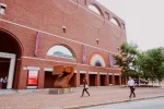 People walk in front of a tall brick building.