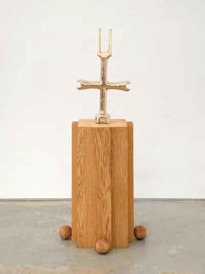 A bronze sculpture of a scaled-up water-shut off wrench that sits atop a wood plinth.
