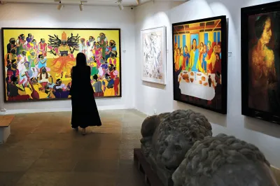 An employee looks at artworks by artists T Vaikuntam (L), K Laxma Goud (2R) and Akbar Padamsee (R) displayed at the AstaGuru auction house gallery ahead of their online auction, in Mumbai on August 29, 2023.