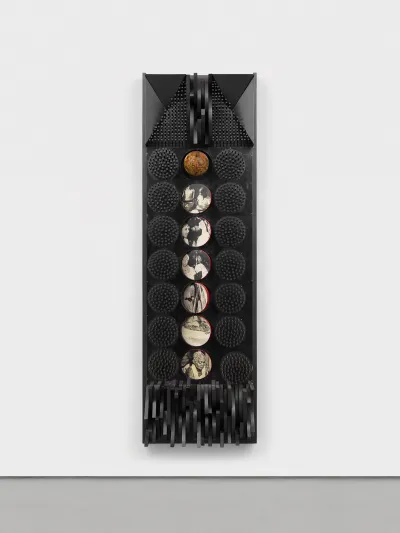 A wall-mounted sculpture that is primarily black with a globe at the center and then archival images in a row below that.
