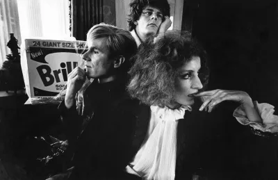 Two men and a woman posed with their hands to the faces.