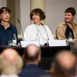 Three women give a press conference.