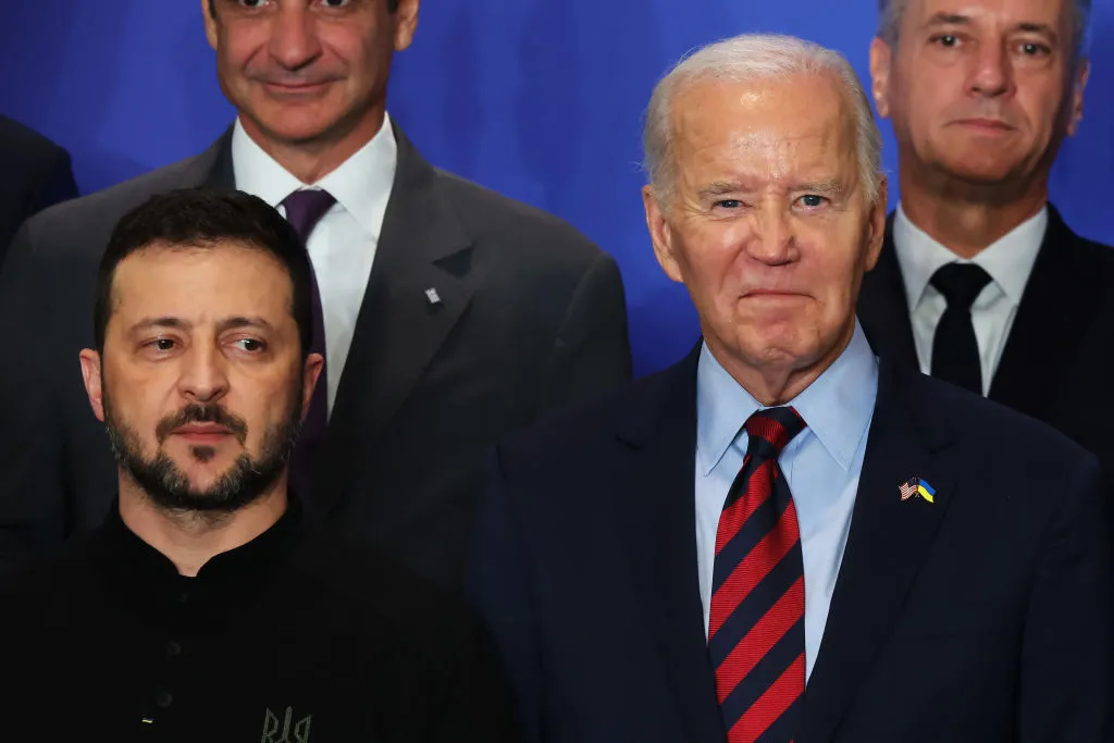 Four suited men stand in front of a blue curtain.