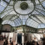 A huge glass-covered roof over exhibitors at a trade fair.