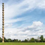 A tall column formed from repeating cast-iron modules in a park.