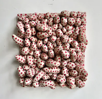 A wall-hung sculpture featuring several tentacle-like pieces of red polka dots on white.