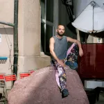 Portrait of Robbie Fitzpatrick, sitting on a giant rock.