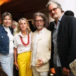 Four people smile for the camera at a party.
