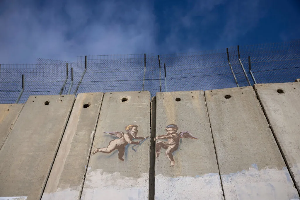 BETHLEHEM, WEST BANK - DECEMBER 23: Evolution of Cherub Wall by Banksy is pictured on Israeli separation wall on December 23, 2023 in Bethlehem, West Bank. Last month, Christian Palestinian leaders here called off public Christmas celebrations, citing the effects of the ongoing war in Gaza. Regarded by Christians as the birthplace of Jesus, Bethlehem is usually bustling with foreign tourists this time of year, with streets full of holiday decoration and vendors selling ornaments and festive figurines. Israel