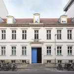 A museum facade with bicycles parked in racks before it.