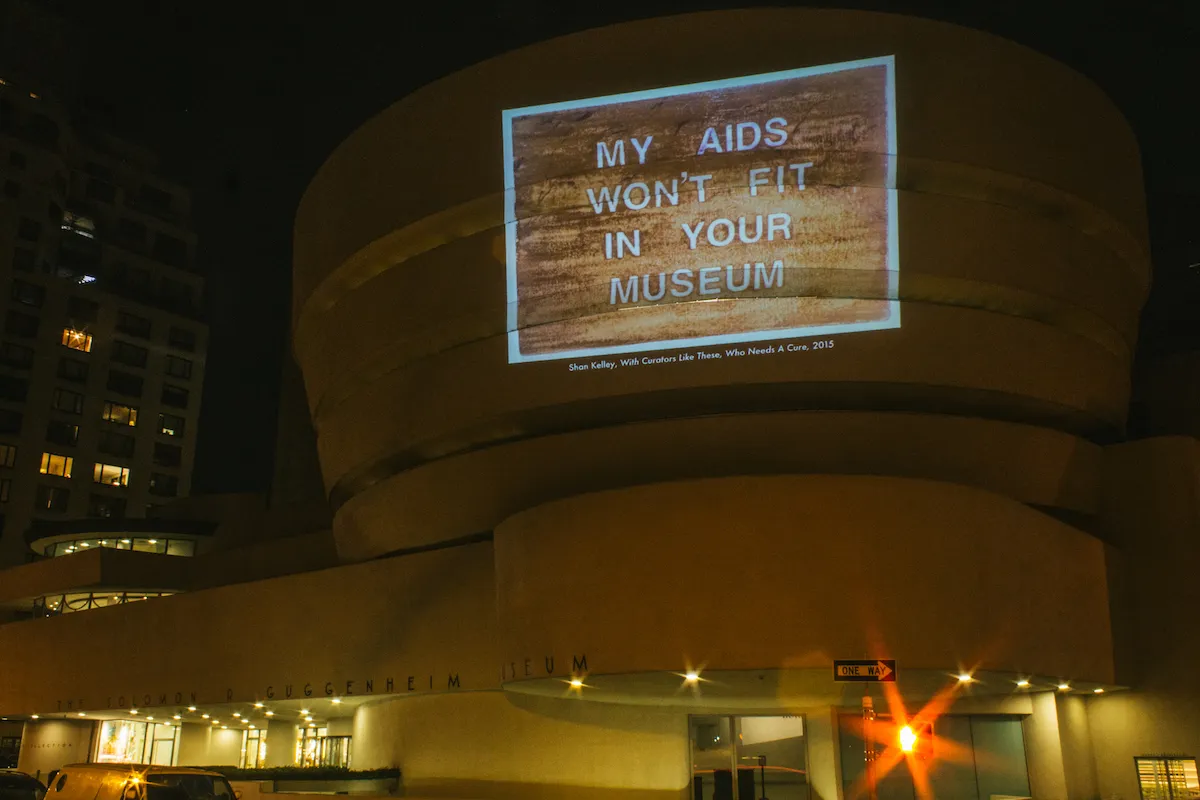 An image is projected on the site of the Guggenheim Museum that reads "My AIDS Won
