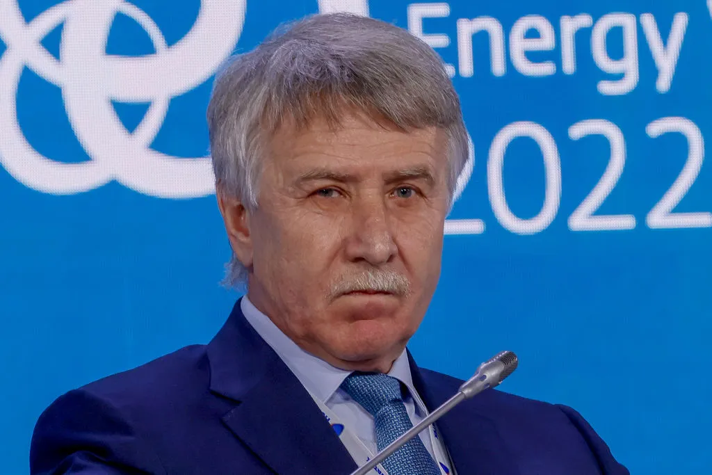 A man with white hair and a white moustache wearing a blue suit.