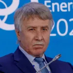 A man with white hair and a white moustache wearing a blue suit.