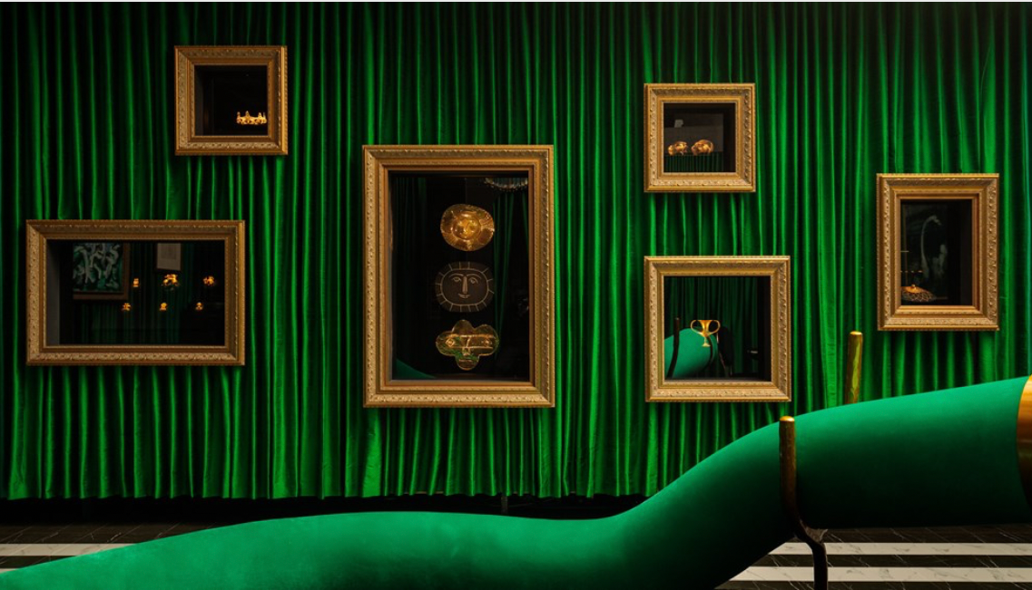Artworks hang in a green velvet-clad room.