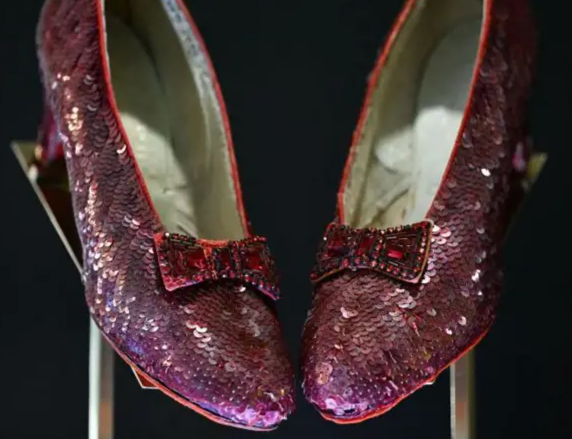 A pair of red sequinned slippers against a black background.