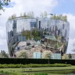 A building in a shape of a bowl, with highly reflective silver surfaces.