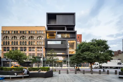 A rendering of a black, blocky museum building next to an office building.
