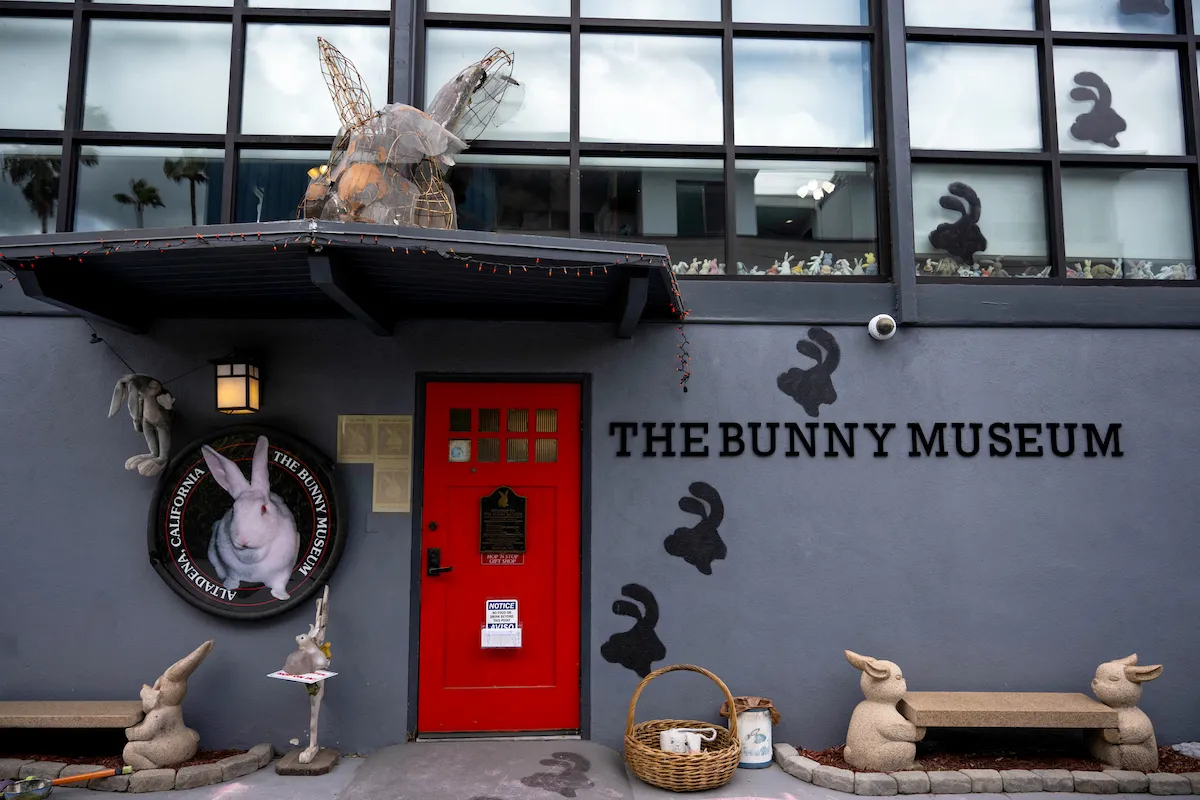 A museum whose facade is covered in images of bunnies. It has a red door, next to which appears the phrase