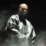 A Black man in a black tracksuit amid fog.