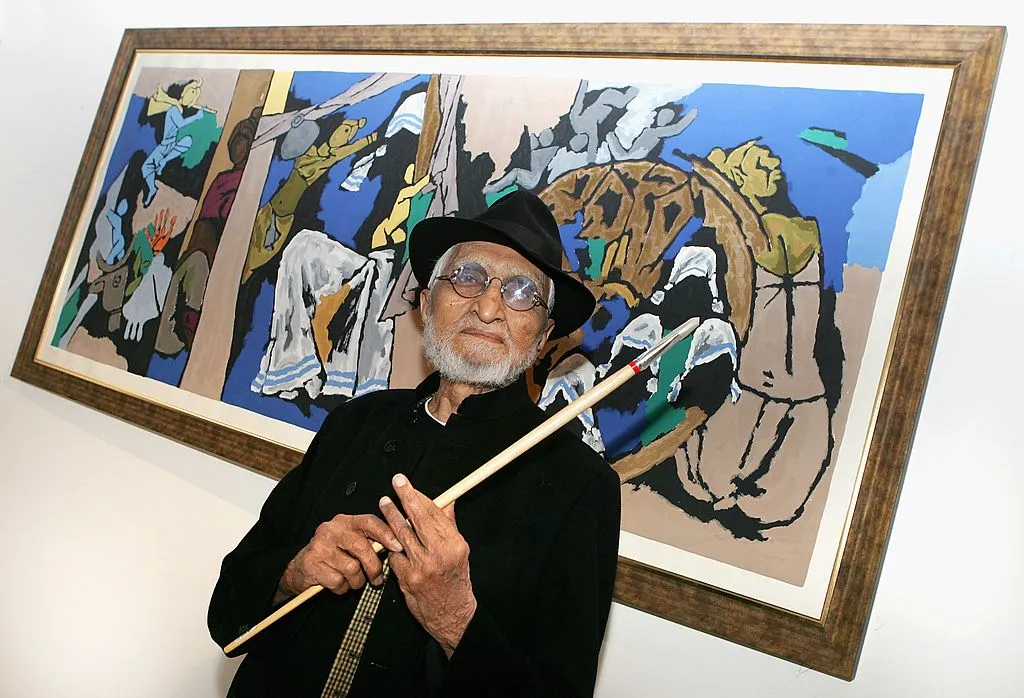 A man with a white beard in front of a painting.