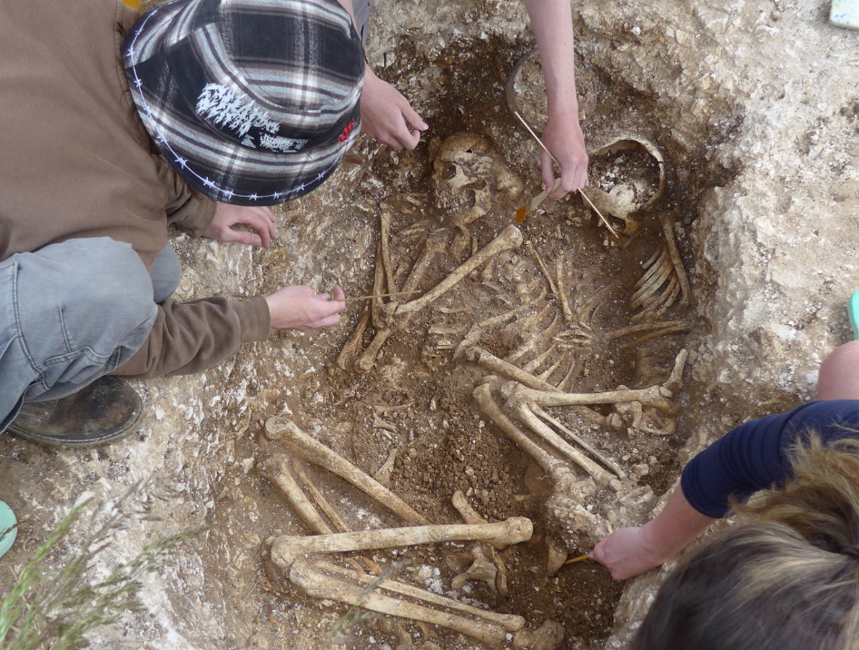 a man looks into a hole containing human remains.
