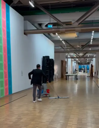 A person with a large dry mop cleaning a museum floor.