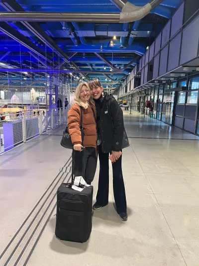Two women stand in the lobby of the Centre Pompidou museum. One holds a suitcase.