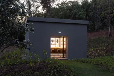 A building with its door open showing a bar in a forest.
