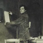 A man pinning a piece of paper to a wall and smiling.