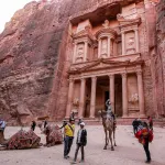 A tourist rides a camel before the site of the Treasury at the ruins of the ancient Nabatean city of Petra in southern Jordan on on December 12, 2022. (Photo by Khalil MAZRAAWI / AFP) (Photo by KHALIL MAZRAAWI/AFP via Getty Images)