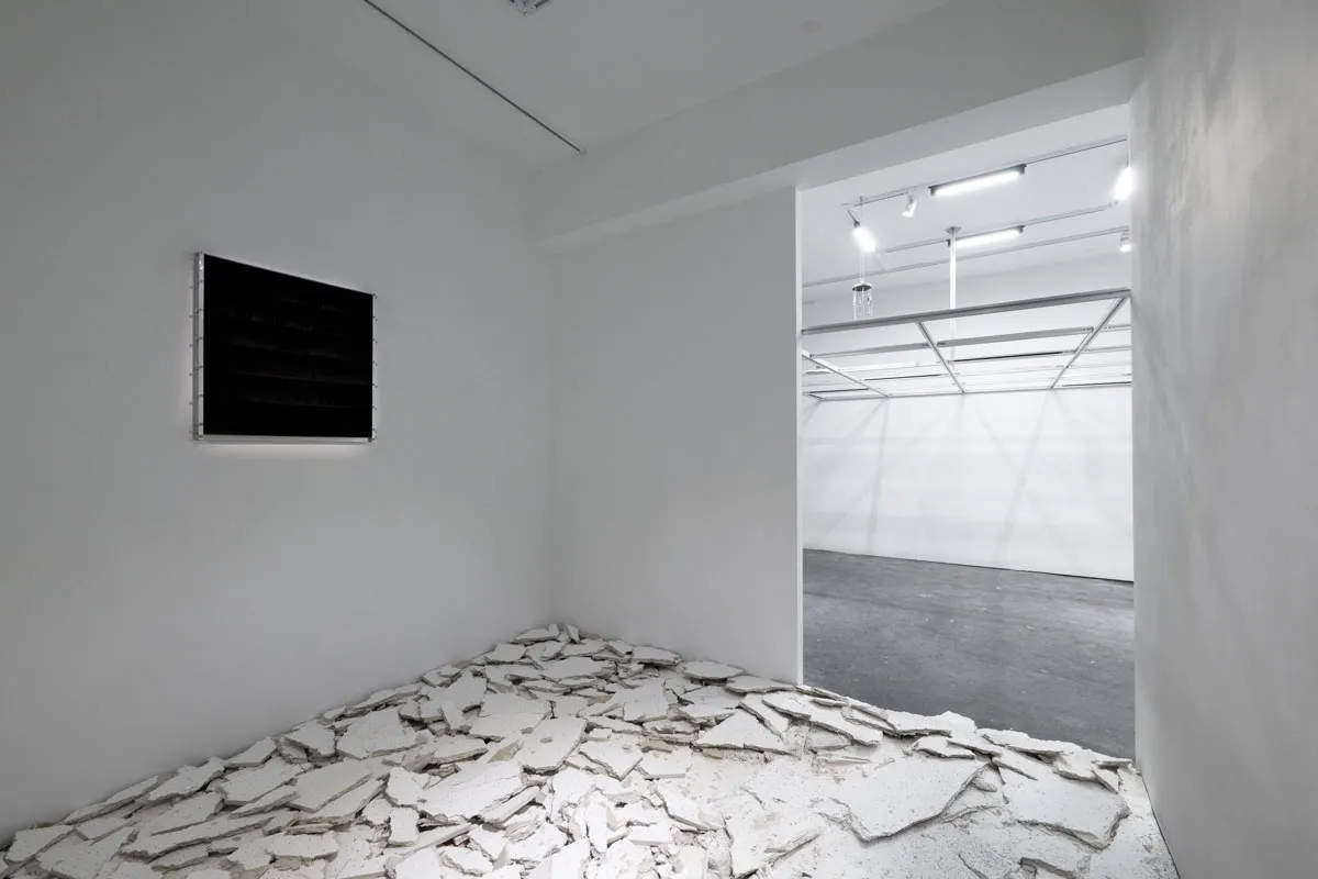 View of a gallery with several pieces of drywall on the floor and a screen on the wall.