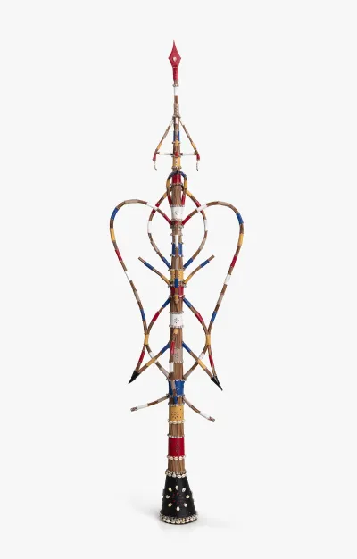 A sculpture resembling a multicolored staff with various hanging elements.