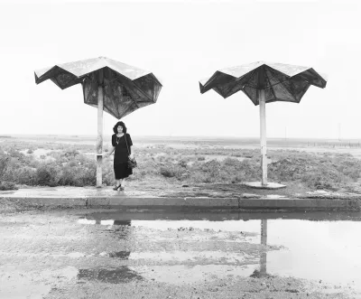 A woman standing beneath a metal umbrella.