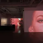 View of an art gallery showing videos on different walls.