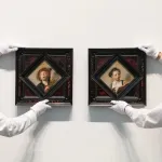 Two guys holding two amazing paintings.