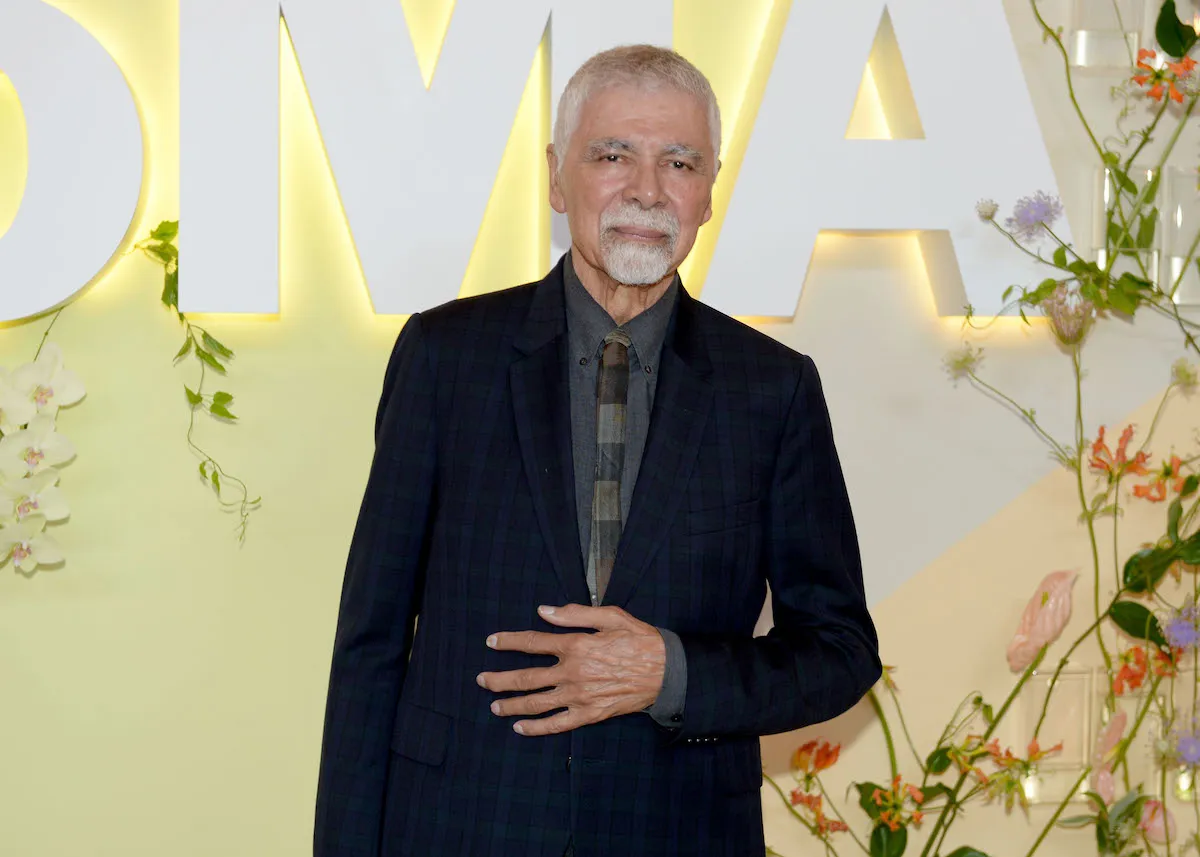 A man in a suit in front of the MoMA logo.