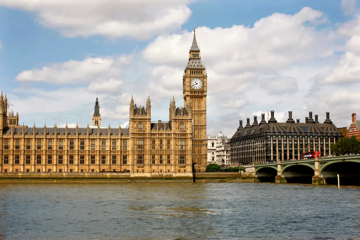 A group of buildings and a clocktower next to a river.