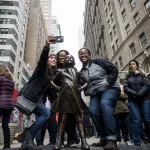People pose next to a bronze sculpture.