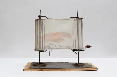 A sculpture resembling a scroll with a hand painted onto its translucent paper.