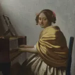 A lovely Vermeer painting of a young woman in a yellow shawl seated at a virginal.
