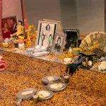 Detail of an altar installation that has mirrored-tiers, photos of Dolores del Rio, fans, rose petals, pink satin fabic, and more.