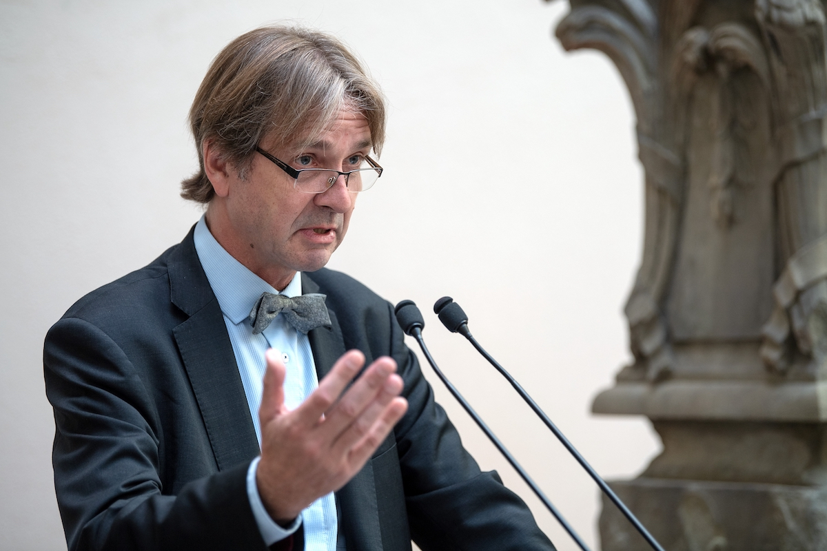 A man speaking at two microphones.